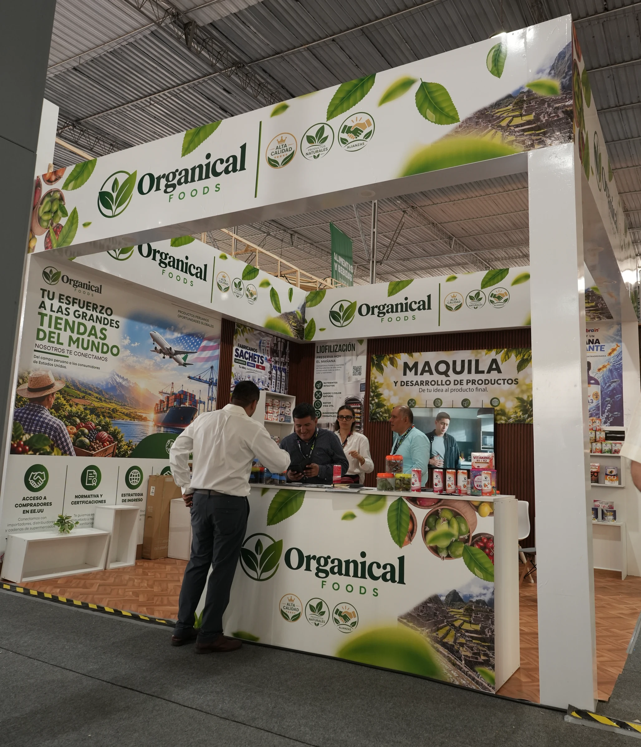 Stand de Organical Foods desde un ángulo lateral, con pórtico rotulado, columna derecha, mostrador y visitantes.